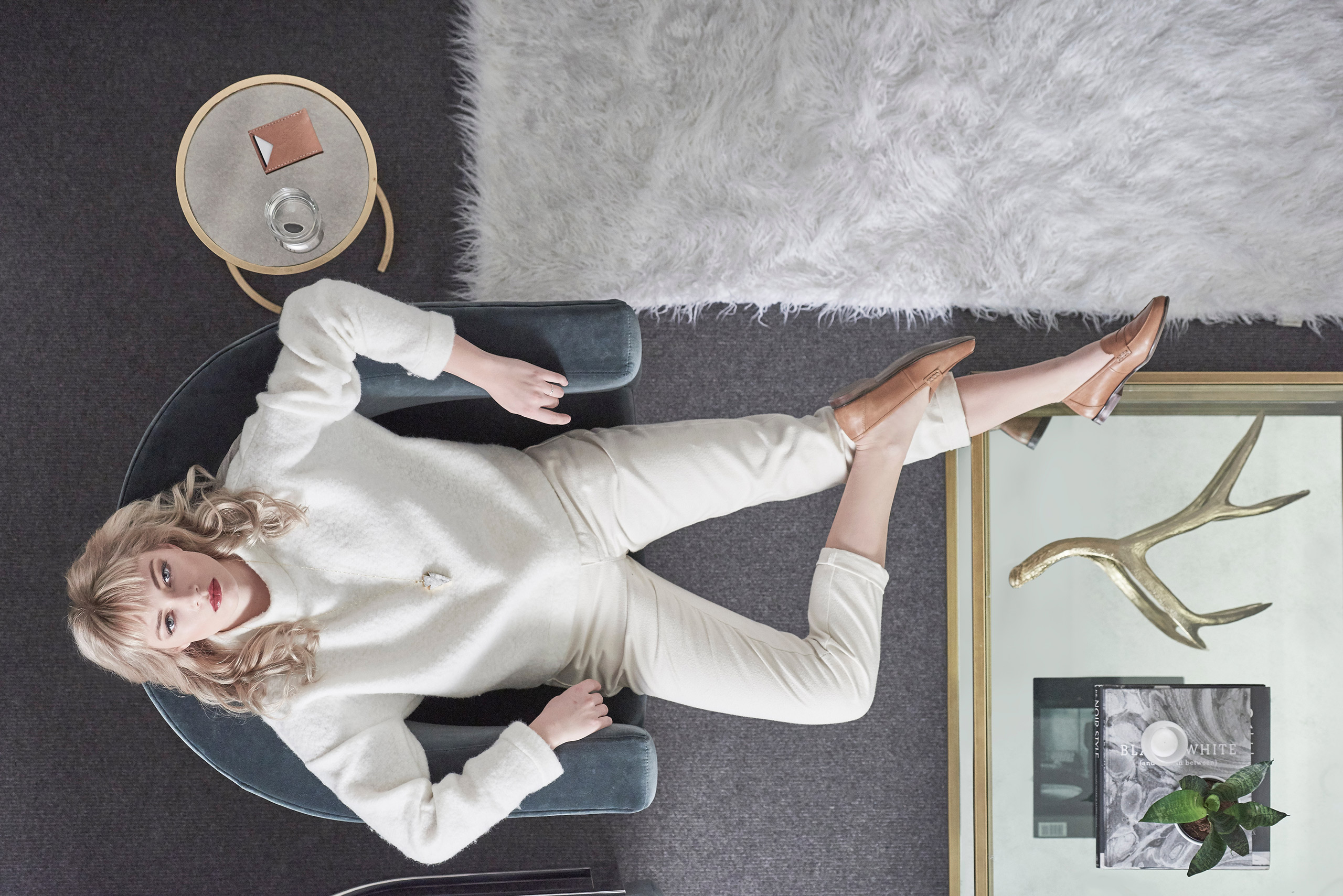 A woman wearing a white sweater is seated comfortably on a chair