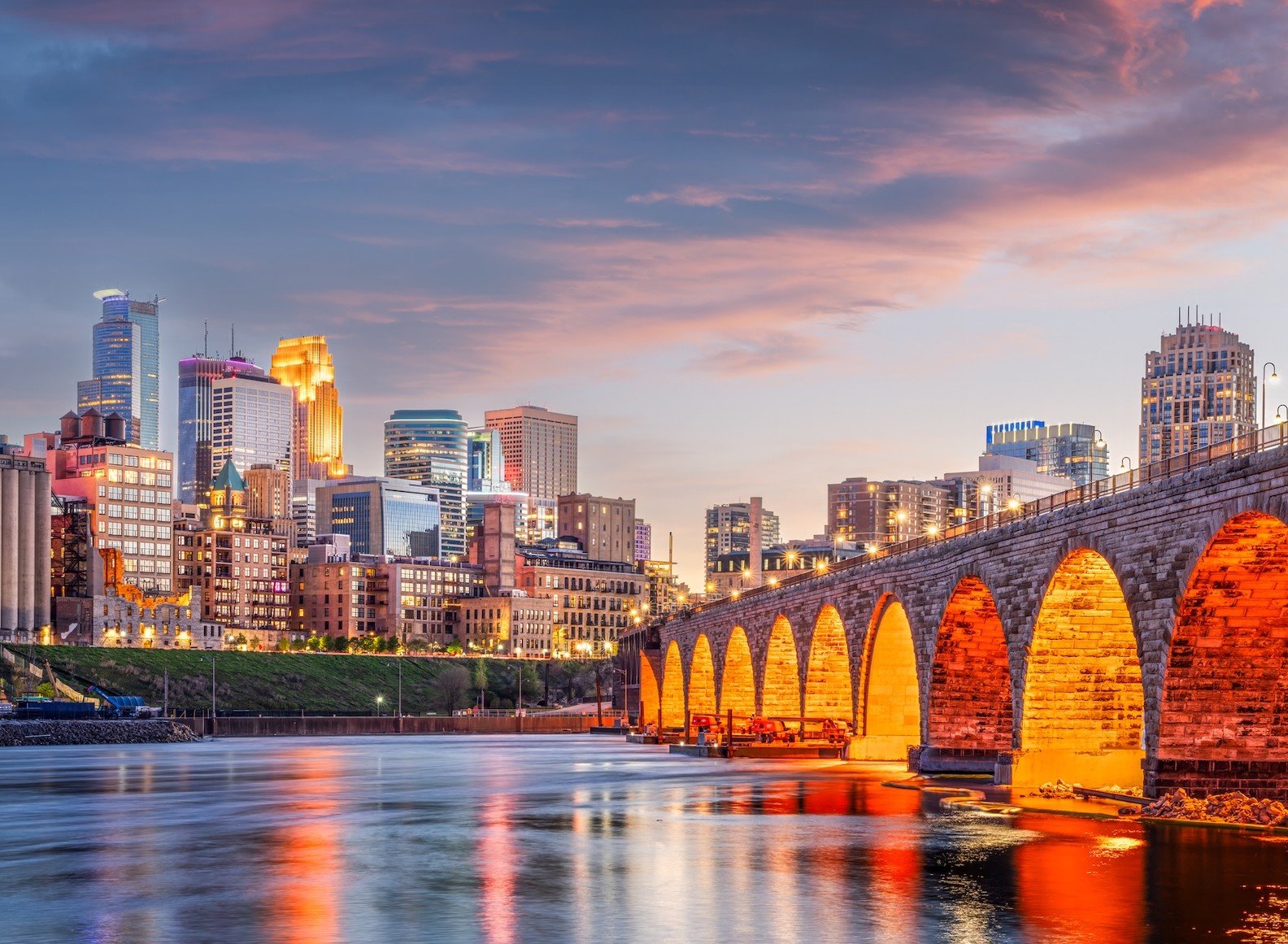 Minneapolis, Minnesota, USA skyline with the Stone Arch Bridge on the Mississippi River at dusk.