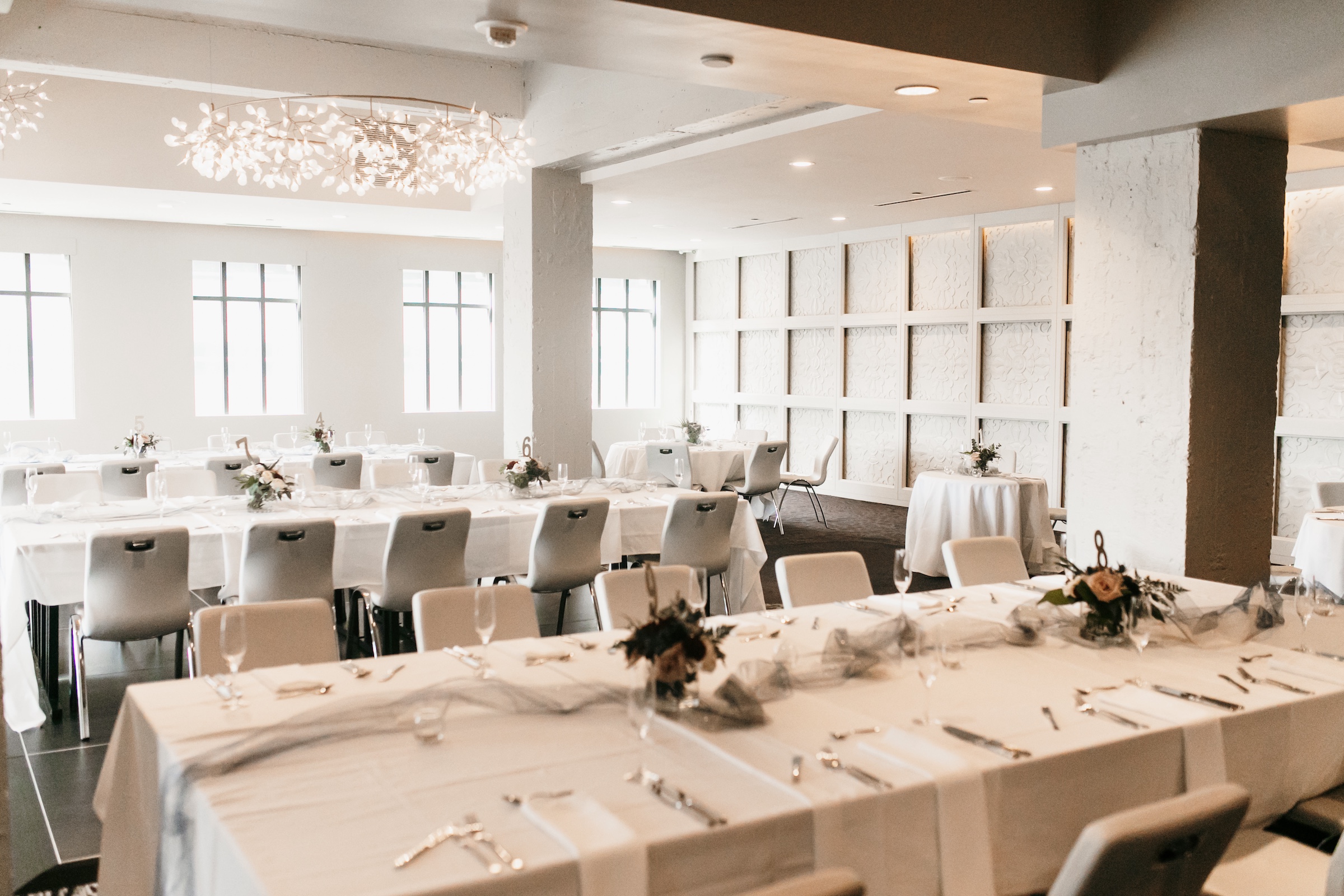 Amber & Brandon's wedding - Dining tables with white cloth under unique lights in a modern venue for Amber and Brandon's wedding