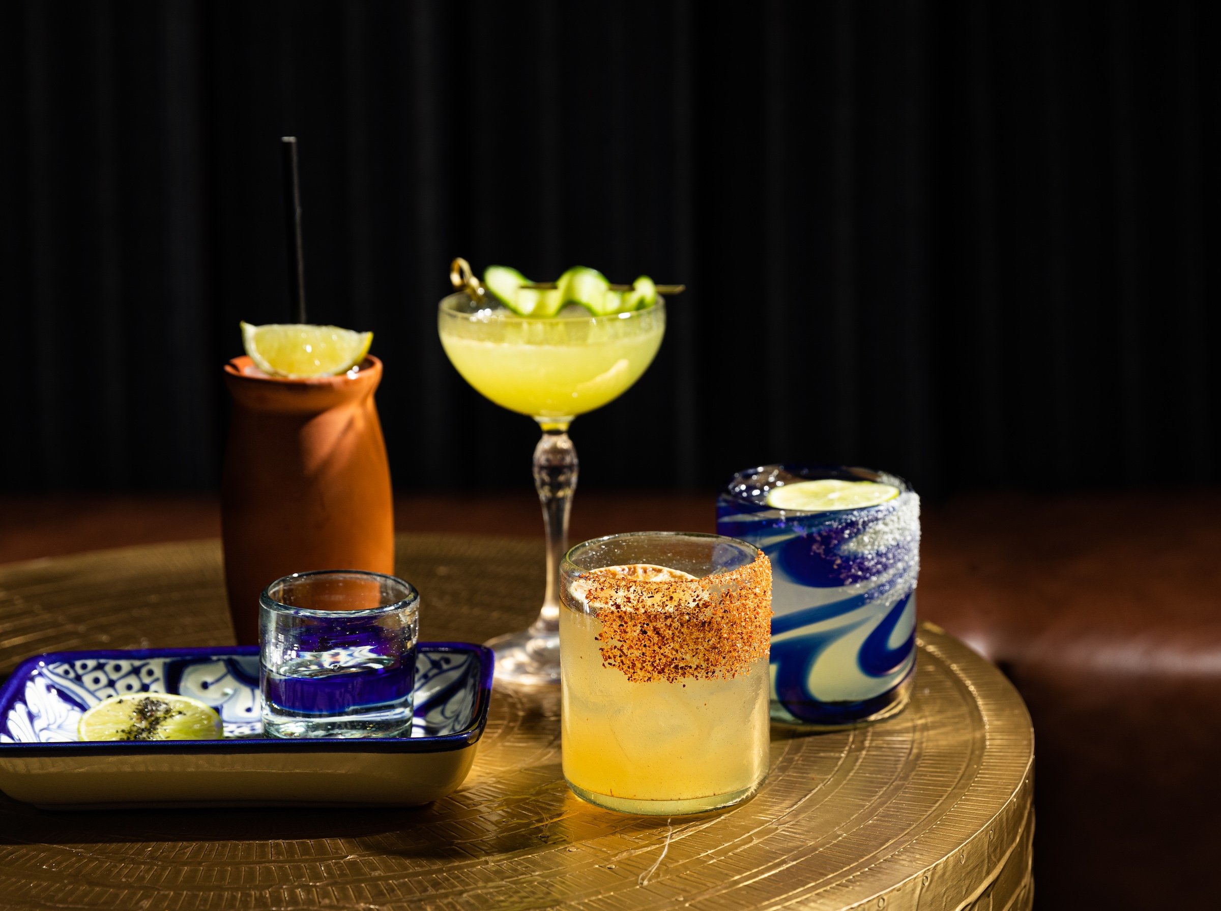 Various cocktails and margaritas on a golden table at Masa & Agave, Hotel Ivy