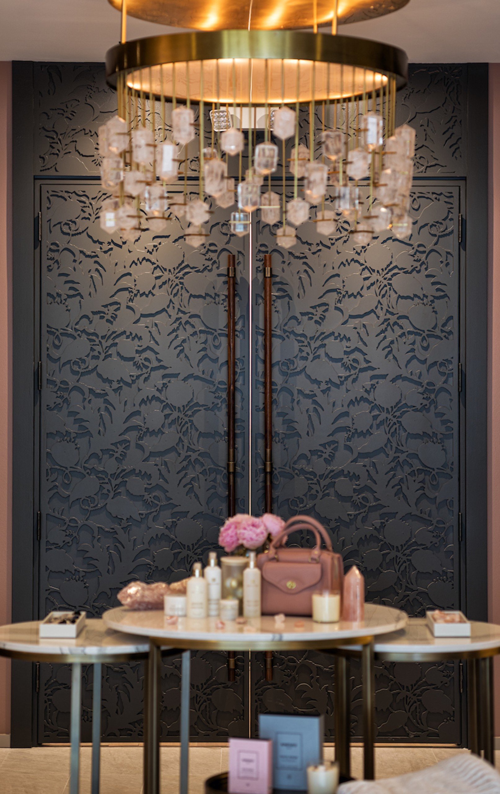 Amenities displayed on white marble tables under unique chandelier at Anda Spa of Hotel Ivy