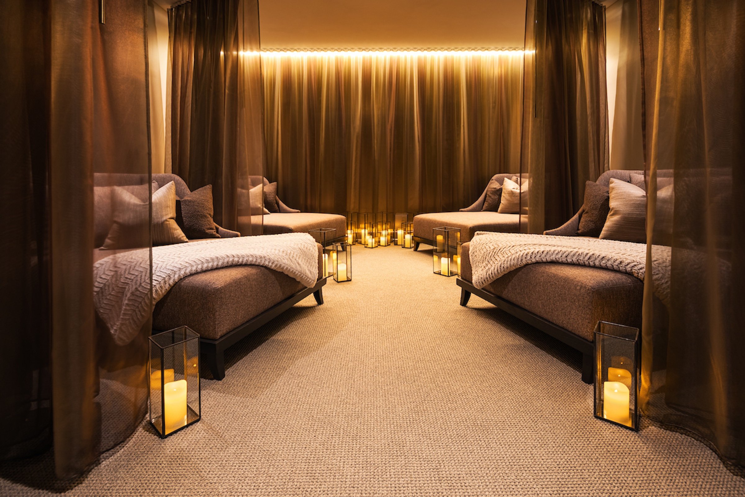 Four large spa couches with black private curtains in a relaxing aura lounge at Anda Spa of Hotel Ivy