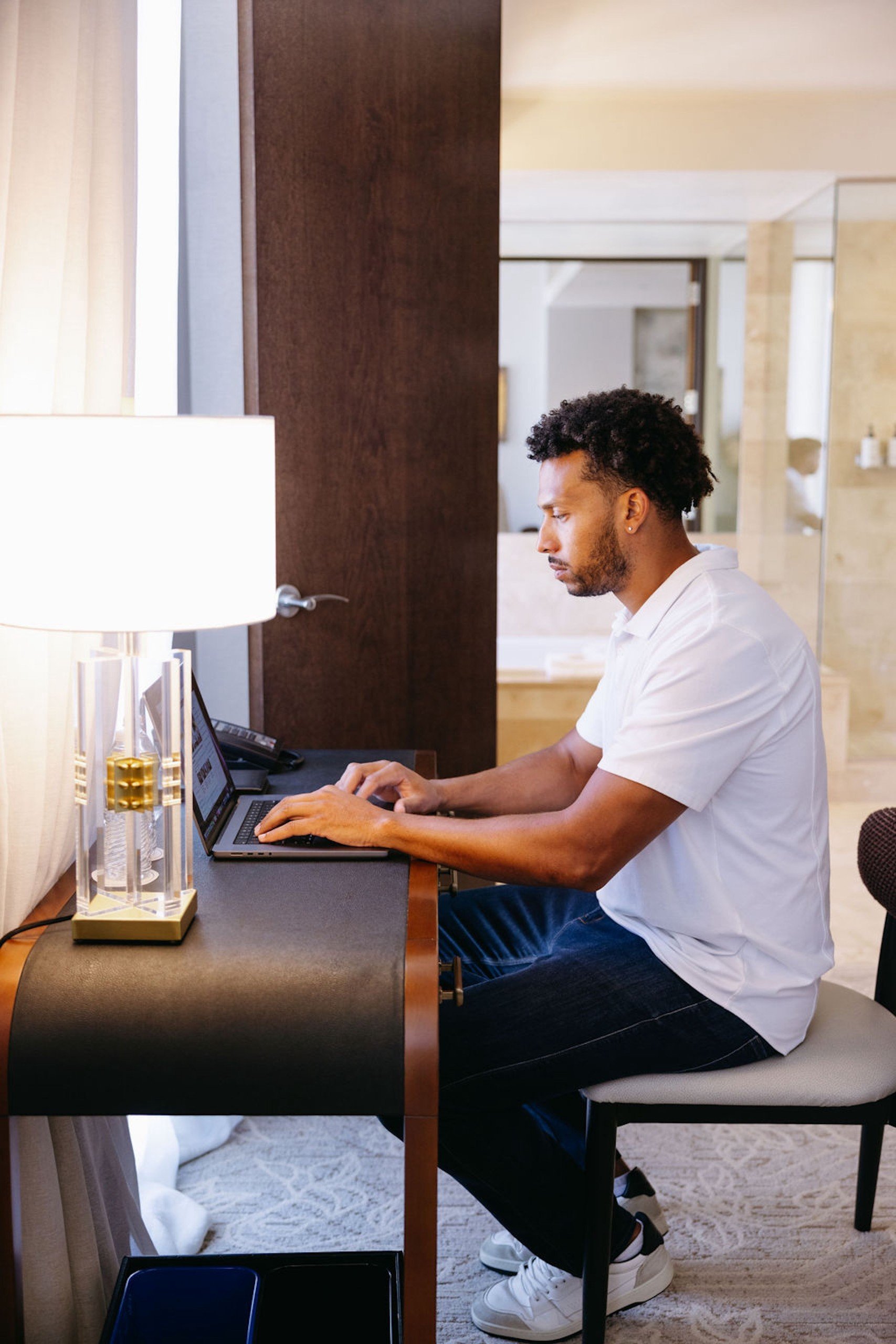 A man with curly hair checking the laptop on the table in a bight space at Anda Fitness of Hotel Ivy