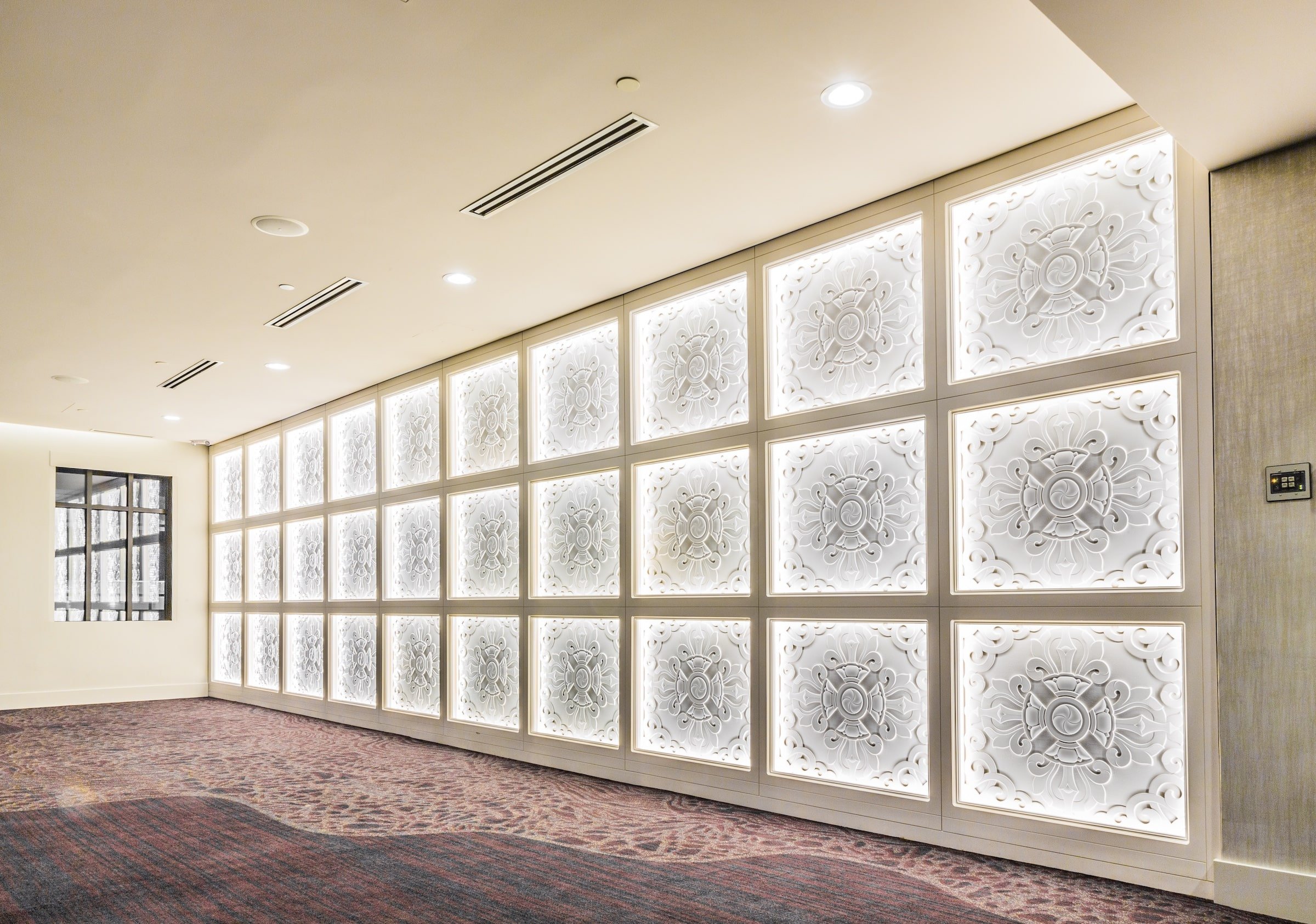 A detailed view of an illuminated decorative wall in Hotel Ivy’s Grand Studio, showcasing an intricate floral pattern with backlighting, adding elegance to the venue.